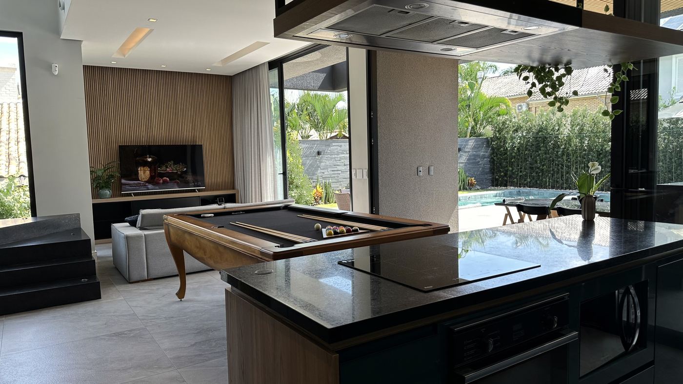 A cozinha, com a ilha central e a porta aberta para a piscina