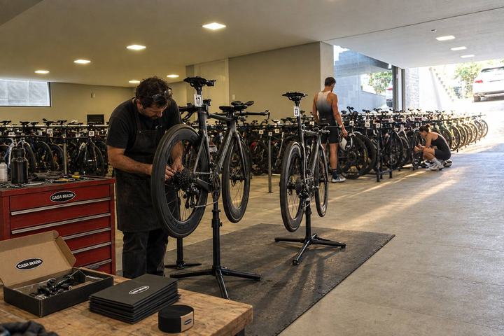 Simulação da garagem com mecânico ajustando uma bike de triatlo no cavalete